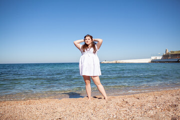 Beautiful plus size woman walking in the beach, resting and enjoy the moment to be alone and meditate near the sea or ocean in the beach. Overweight woman wearing dress