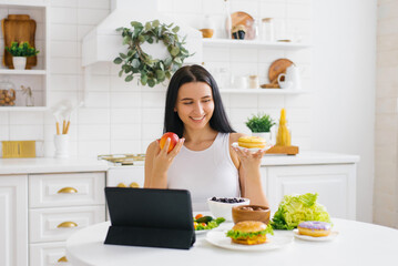 Happy woman nutritionist holds an online lesson or conference in the kitchen on the topic of...