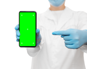Cropped shot of a doctor in a blue medical mask and gloves holding smartphone with greenscreen and tracking points, pointing finger on it. Isolated on white, copy space.