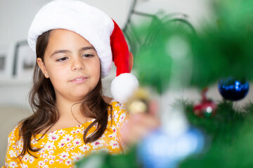 Closeup of little child decorating Christmas tree at home. Space for text.
