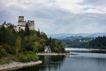 Fototapeta na wymiar Ancient castle Dunajec in Nedzice, Poland, Europe. Landscape with an old castle on a hill above the lake on a cloudy day.