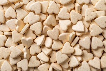 Pet supplement tablets background. Macro texture of heart shaped pills for cats and dogs. Vitamin vegan treats for domestic animals closeup. Veterinary nutritional supplement concept.
