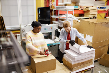 High angle view at workers opening boxes with paper in industrial print shop, copy space - obrazy, fototapety, plakaty
