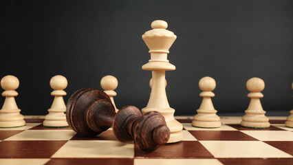 A white chess queen against the background of an army of white pawns.Defeat of the black queen...