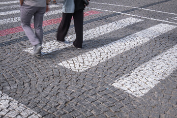 People walking on the cobblestone pavement. natural stone paved street floor.