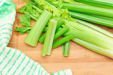 Fresh Celery Stem and Chopped Celery Sticks on Wooden Cutting Board. Vegan and Vegetarian Culture. Raw Food. Healthy Diet with Negative Calorie Content. Slimming Food