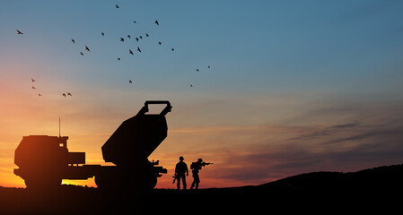 Artillery rocket system are aimed to the sky and soldiers at sunset. Multiple launch rocket system.