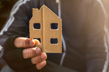 Obdachloser hält ein Haus aus Pappe in der Hand