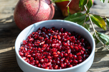 Raw pomegranate (Punica granatum) seeds ready to be eaten. Close up on pomegranate arils with fruits in the background.