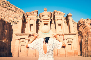 Caucasian woman tourist in white dress hold her white hat pose at Ad Deir or El Deir, the monument...