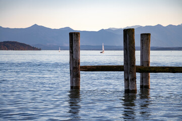 Wooden pier on the lake Starnberg, Bavaria, Germany, with mountains and sailboats in the background