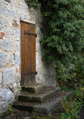 Wooden door in an old medieval wall with stone steps