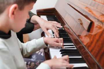 Little boy plays the piano for the first time, mom shows how to play and explains musical notation,...