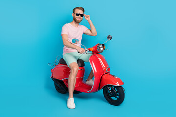 Obraz na płótnie Canvas Full size photo of handsome young guy riding moped enjoy weekend dressed stylish pink clothes isolated on aquamarine color background
