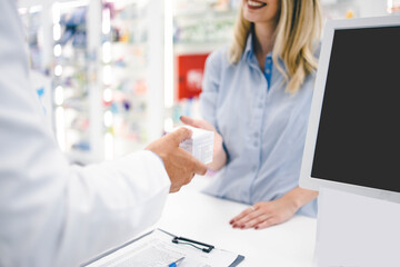 Young woman in phamracy store, looking to by some healthy suplements. Pharmacy worker is helping her