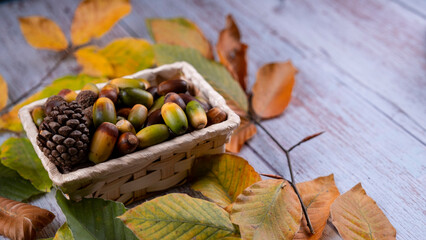 Heart shaped acorn among autumn leaves on wooden table, image with space for text