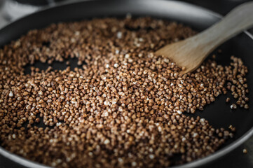 Buckwheat, fried in a pan and a wooden spatula.