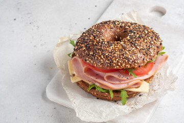 bagel filled with rocket, turkey ham, cream cheese and tomato