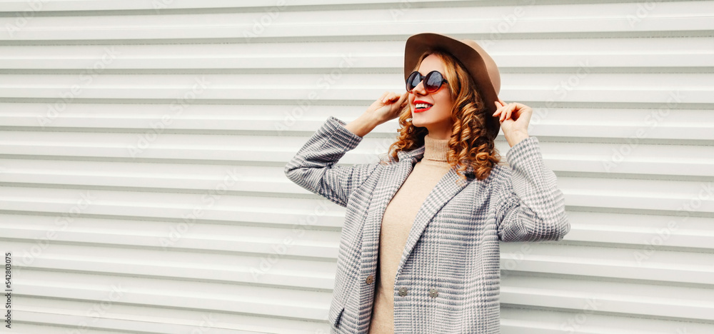 Wall mural Portrait of beautiful smiling young woman looking away wearing coat jacket with round hat on white background, blank copy space for advertising text