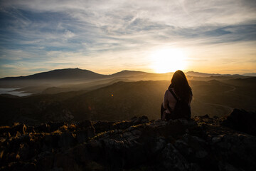 Beautiful women sitting on a rock during sunset on the mountains