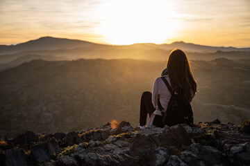 Beautiful women sitting on a rock during sunset on the mountains - obrazy, fototapety, plakaty