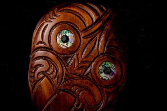 Wooden Maori Hei Tiki Hand Carved With Paua Shell Eyes. New Zealand Taonga. Closeup Dark Background.