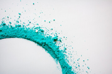 Turquoise colored powder whirlwind on white background