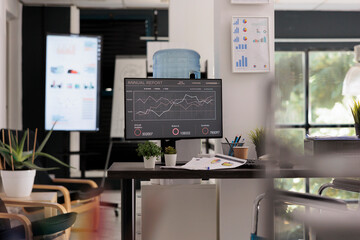 Modern workspace interior of a new start up company in financial district, with no people working in it, disabled friendly office. Screen in the background with sales statistics for next staff meeting