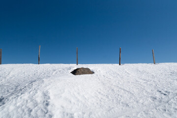 white snow and blue sky divided by wooden poles of a fence