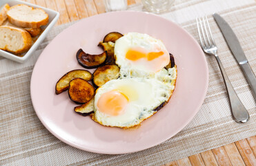 Healthy lunch of pan fried eggs with liquid yolk and slices of aubergine served on plate ..