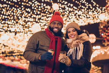 Fototapeta premium Photo of charming positive boyfriend girlfriend dressed winter season outfits trying x-mas beverages outdoors urban city street