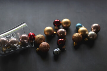 Glass with colorful Christmas baubles on dark background. Selective focus.