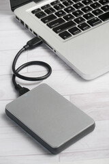 working at office, laptop on the table connected USB Cable with External Hard Drive