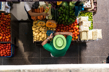 man with green shirt buying vegetables in brazil