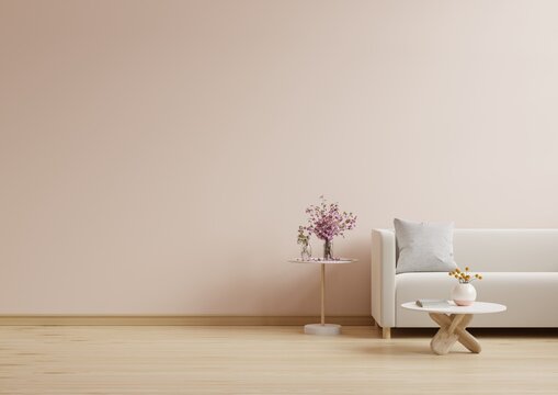 Cream sofa with table on light pink wall and wooden flooring.