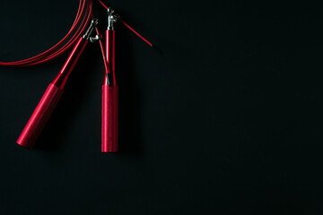 Red skipping rope isolated on black background.