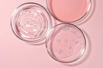 Petri dishes with liquids on pale pink background, flat lay