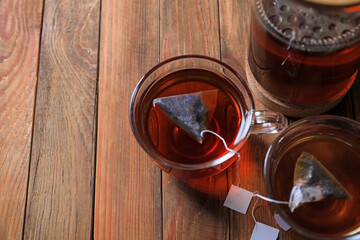 Tea bags in cups on wooden table, above view. Space for text