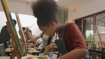 A Black girl concentrates on acrylic color picture painting on canvas with multiracial kids in an art classroom, creative learning with talents and skills in the elementary school studio education. - Powered by Adobe