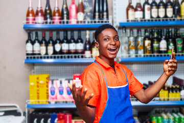 shot of surprised young handsome black shop owner holding mobile phone and smiling looking at camera