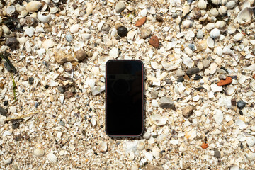 Smartphone lies on shells on the seashore, it has been lost. Flatley. copy space. 