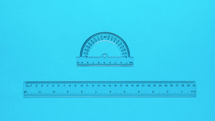 Transparent protractor and transparent ruler on a blue background.
