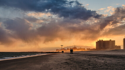 Sudden sand storm on the beach at Coney Island at Sunset with masked passerby people