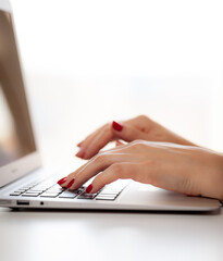 The girl behind the laptop. Female hands typing text on the keyboard while exchanging messages via social networks using laptop. A female office worker checks her email while sitting at a desk