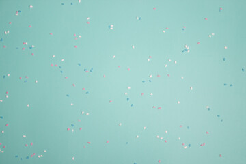 colorful confetti with white, pink and blue over the mint background.