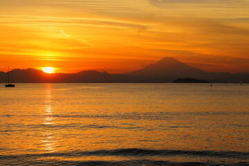 逗子海岸から見た夕焼けの中に浮かぶ江の島と富士山のシルエット