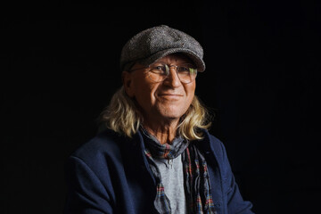 Portrait of a senior man smiling against a dark background