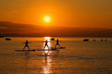 夕暮れの逗子海岸、オレンジに染まる海でSUPヨガを楽しむ女性たち