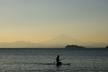 秋の夕暮れの逗子海岸、SUPを楽しむ若者