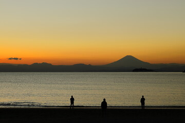日没後にオレンジ色に染まる空と富士山のシルエットとそれを眺める人たち